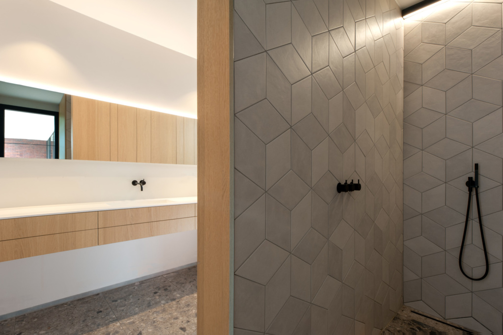 Moderne badkamer met open douche achter muur met Shinnoki Natural oak eik fineer wandbekleding en ladefronten