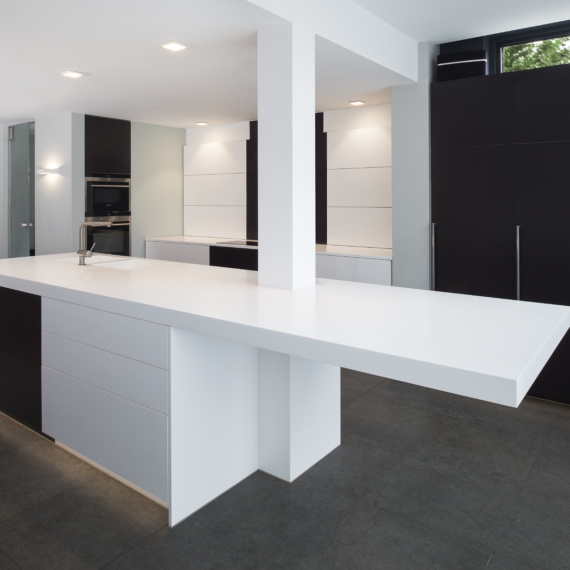 Strakke monochrome moderne keuken met ingebouwde dampkap afzuigsysteem in wand met wit natuursteen tablet